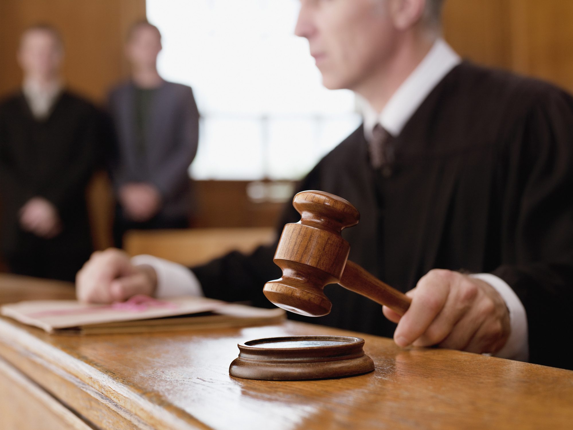 Judge holding gavel in a courtroom.